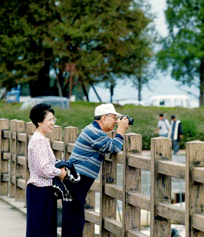  Ikeda sensei visita o Centro Cultural Shiga, localizado às margens do Lago Biwa. Ele caminha pelos arredores com a Sra. Kaneko e aponta sua câmera para a magnífica paisagem do lago (cidade de Otsu, out. 1995)
