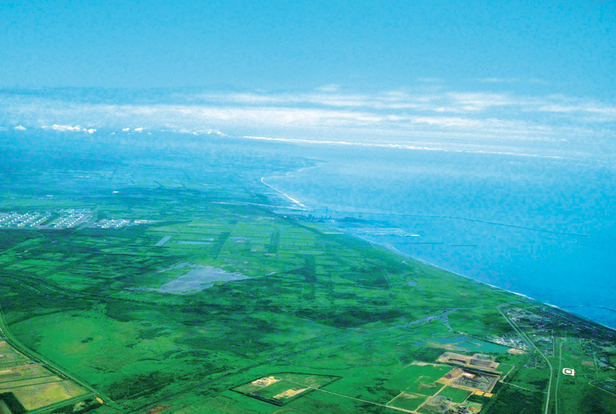 foto aérea de campo verdejante margeado pelo mar